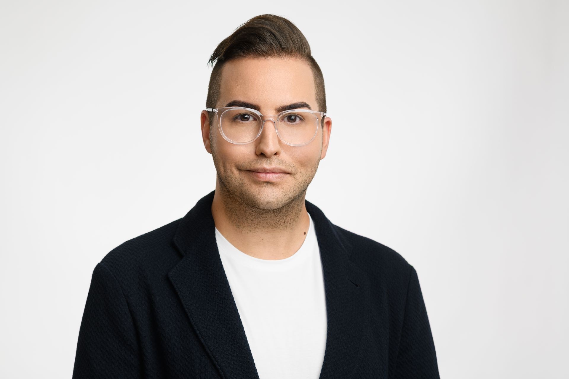 Person wearing a black jacket and white shirt against a white background. Person wearing a black jacket and white shirt against a white background.